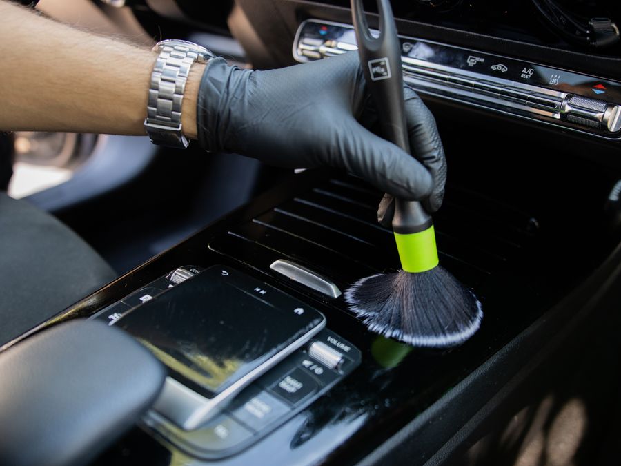 Curățarea consolei centrale cu pensulă, în timpul unei lucrări de detailing interior
